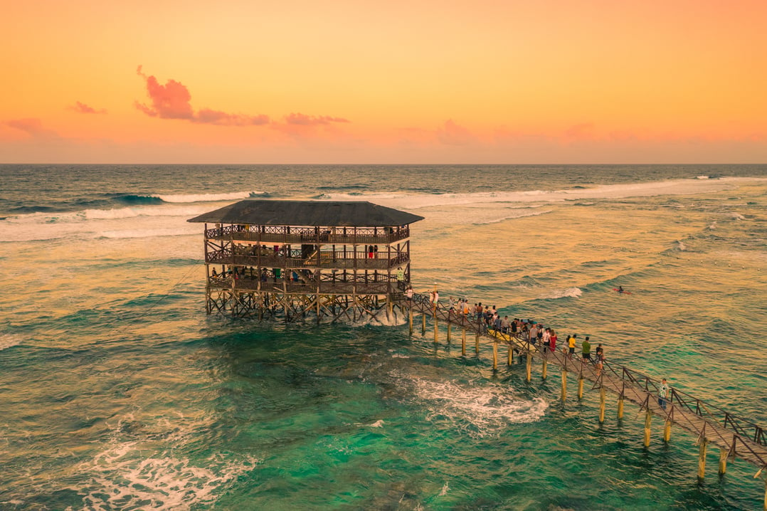 Sunset on most popular surfing area Cloud 9 at Siargao, Philippines. Aerial view raised wooden walkway for surfers to cross the reef of siargao island to cloud 9 surf break Mindanao.